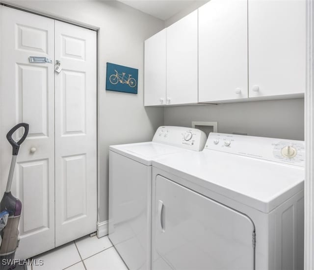 laundry area with washing machine and dryer, light tile patterned floors, and cabinets