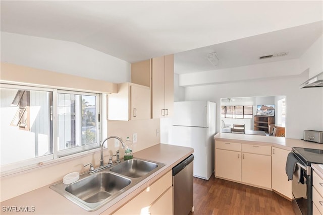 kitchen with sink, vaulted ceiling, dark hardwood / wood-style floors, appliances with stainless steel finishes, and cream cabinetry