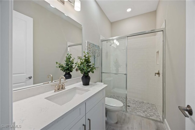 bathroom featuring hardwood / wood-style flooring, vanity, toilet, and walk in shower