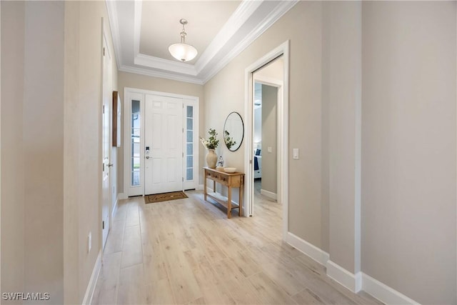 entryway featuring light wood-type flooring, a tray ceiling, and ornamental molding