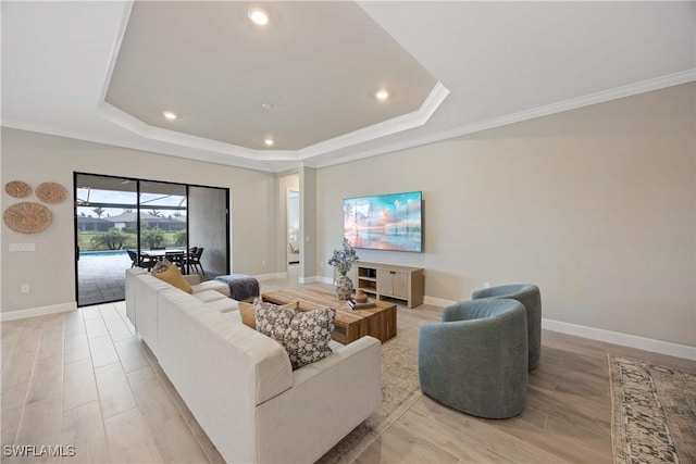 living room with a tray ceiling, light hardwood / wood-style floors, and ornamental molding