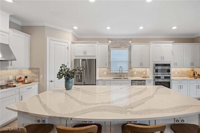 kitchen featuring stainless steel appliances, a spacious island, sink, white cabinetry, and a breakfast bar area