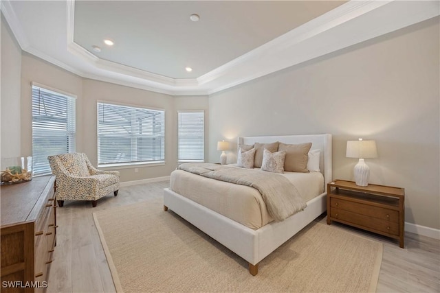 bedroom featuring a raised ceiling, ornamental molding, and light wood-type flooring