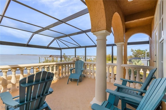 view of patio with a lanai and a water view