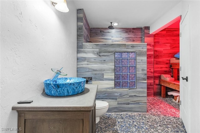 bathroom with vanity, tile walls, and toilet