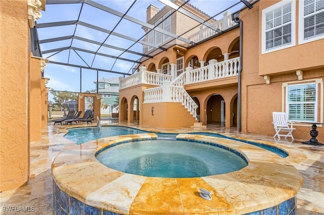 view of swimming pool featuring glass enclosure, an in ground hot tub, and a patio