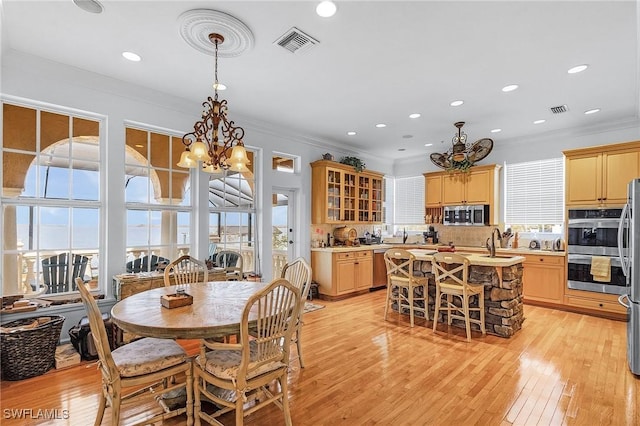 dining room with sink, light hardwood / wood-style flooring, a chandelier, and ornamental molding