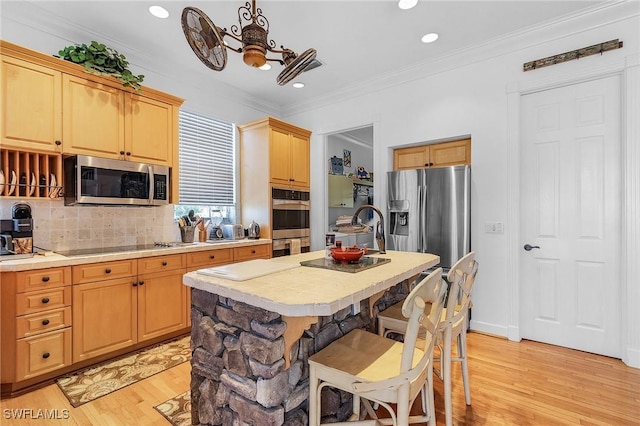 kitchen featuring decorative backsplash, stainless steel appliances, ceiling fan, a center island with sink, and light hardwood / wood-style floors