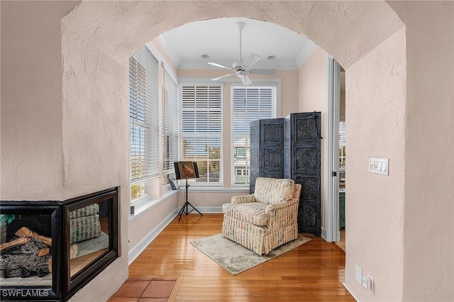 sitting room with hardwood / wood-style floors, ceiling fan, and ornamental molding