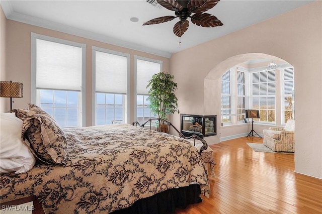 bedroom with ceiling fan, light hardwood / wood-style floors, a water view, and ornamental molding