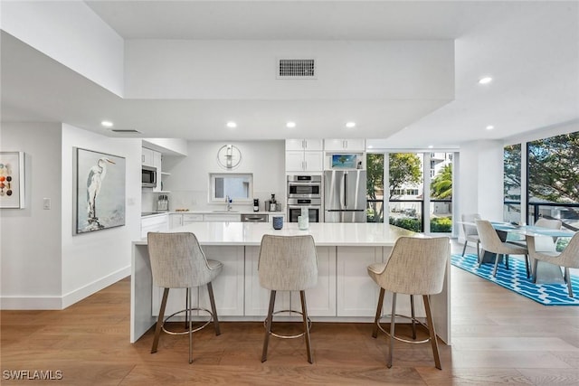 kitchen featuring a kitchen bar, appliances with stainless steel finishes, and white cabinetry