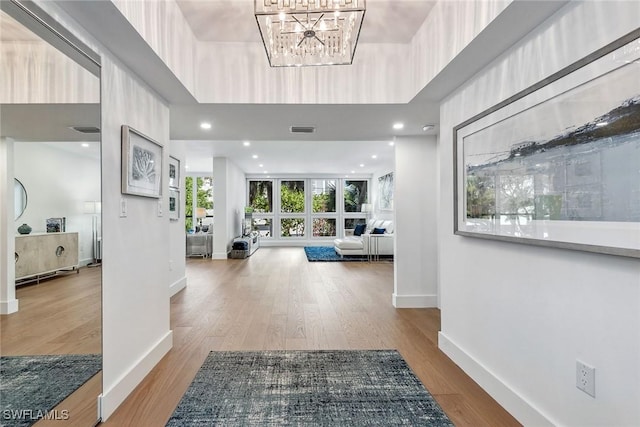 entrance foyer with a chandelier, a tray ceiling, and light hardwood / wood-style flooring