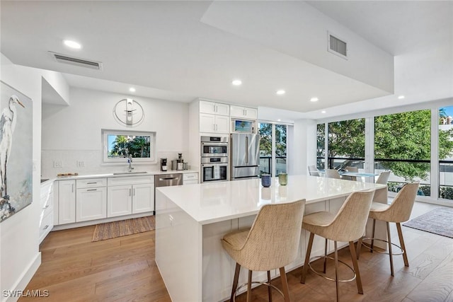 kitchen featuring a kitchen island, white cabinetry, stainless steel appliances, and a wealth of natural light