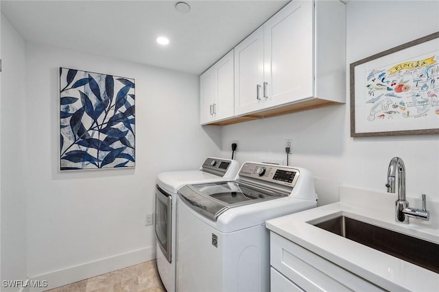 clothes washing area with cabinets, washing machine and dryer, and sink