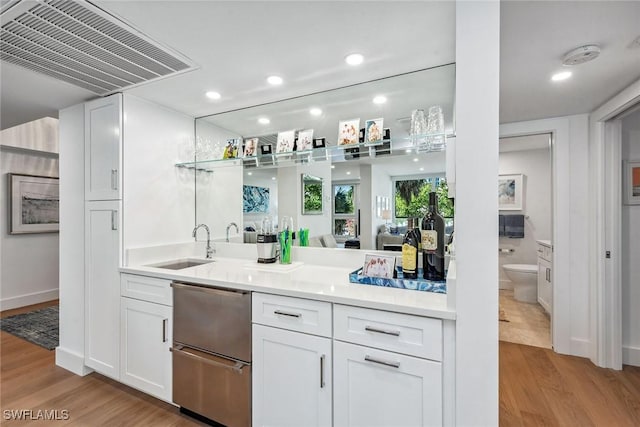 bar featuring white cabinets, sink, and light hardwood / wood-style flooring