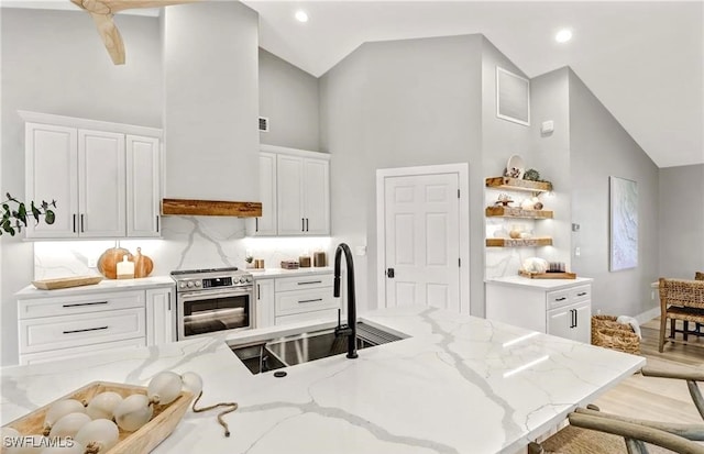 kitchen featuring white cabinetry, sink, backsplash, stainless steel electric range, and a breakfast bar