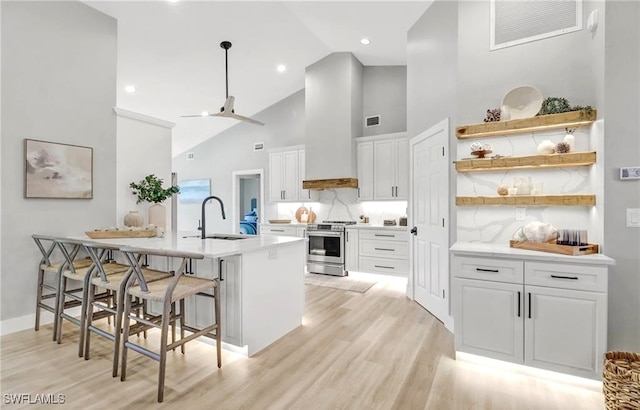 kitchen featuring a kitchen breakfast bar, stainless steel range oven, white cabinetry, and sink