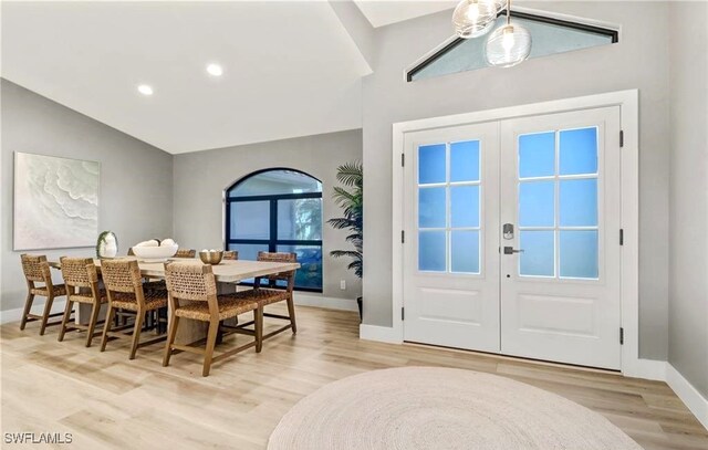 dining area with vaulted ceiling, light hardwood / wood-style flooring, and french doors