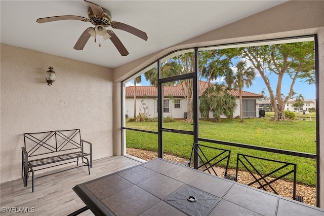 unfurnished sunroom featuring ceiling fan, a healthy amount of sunlight, and vaulted ceiling