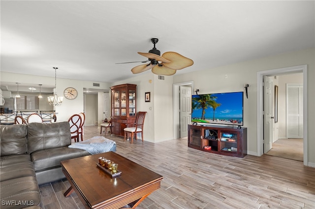 living room with ceiling fan with notable chandelier and light hardwood / wood-style floors