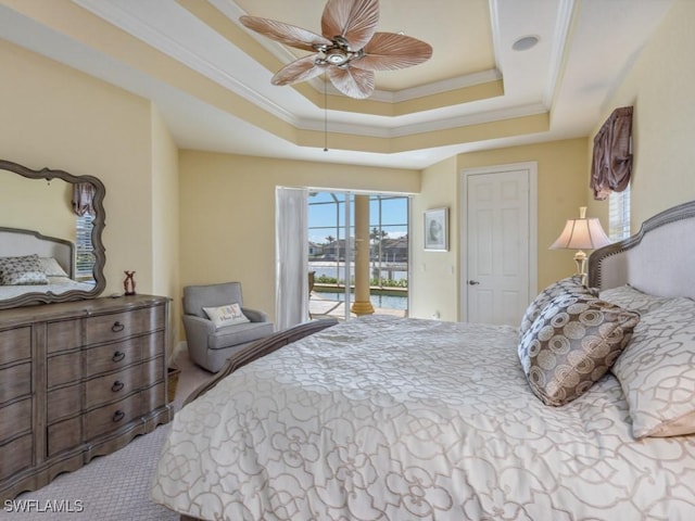 carpeted bedroom featuring access to exterior, a tray ceiling, ceiling fan, and ornamental molding