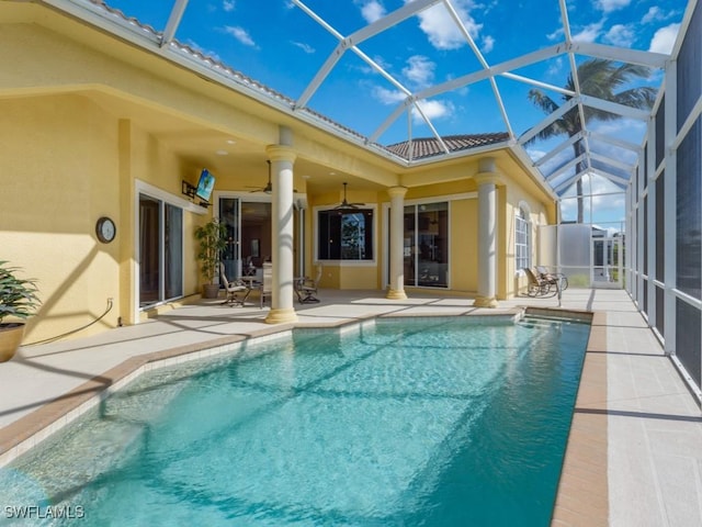 view of pool featuring glass enclosure, a patio area, and ceiling fan