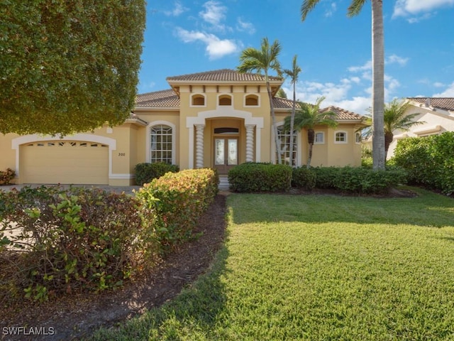 mediterranean / spanish-style house featuring a garage, a front yard, and french doors