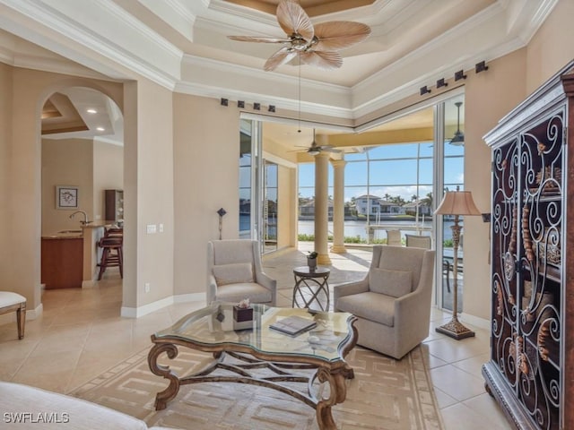 living area featuring ornamental molding, a raised ceiling, ceiling fan, light tile patterned floors, and a water view