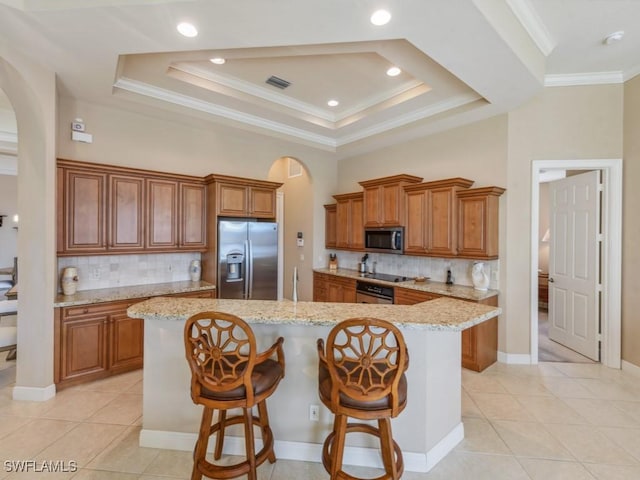 kitchen featuring a center island, stainless steel appliances, tasteful backsplash, a kitchen bar, and light tile patterned flooring