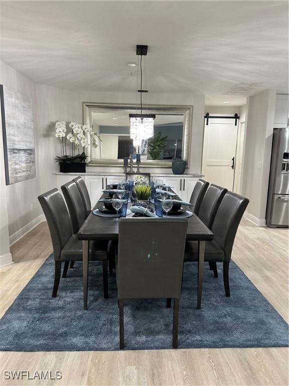 dining space with a chandelier, a barn door, and light hardwood / wood-style flooring