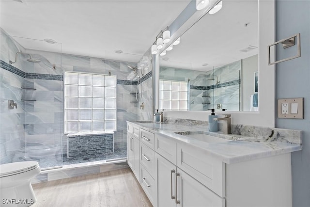 bathroom with hardwood / wood-style floors, vanity, toilet, and a shower with door