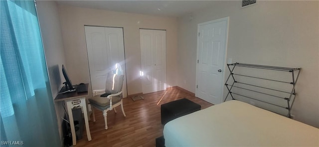 bedroom featuring multiple closets and dark hardwood / wood-style floors