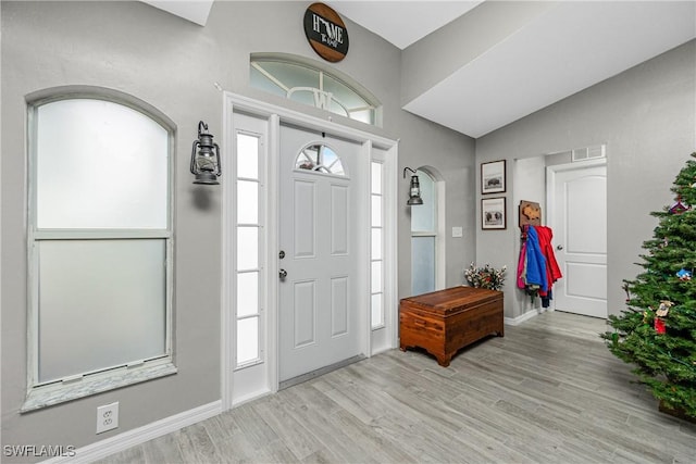 foyer entrance with light wood-type flooring and lofted ceiling