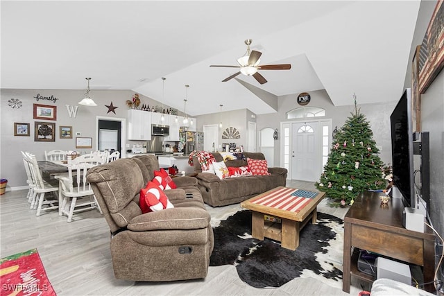 living room featuring ceiling fan, light hardwood / wood-style floors, and vaulted ceiling