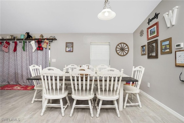 dining room with light hardwood / wood-style flooring and vaulted ceiling