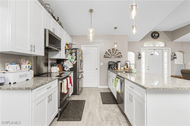 kitchen featuring white cabinetry, sink, hanging light fixtures, stainless steel appliances, and light hardwood / wood-style flooring