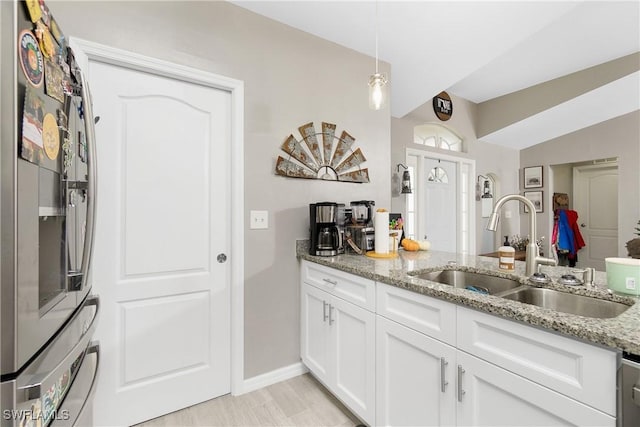 kitchen with light stone countertops, sink, light hardwood / wood-style flooring, white cabinetry, and hanging light fixtures