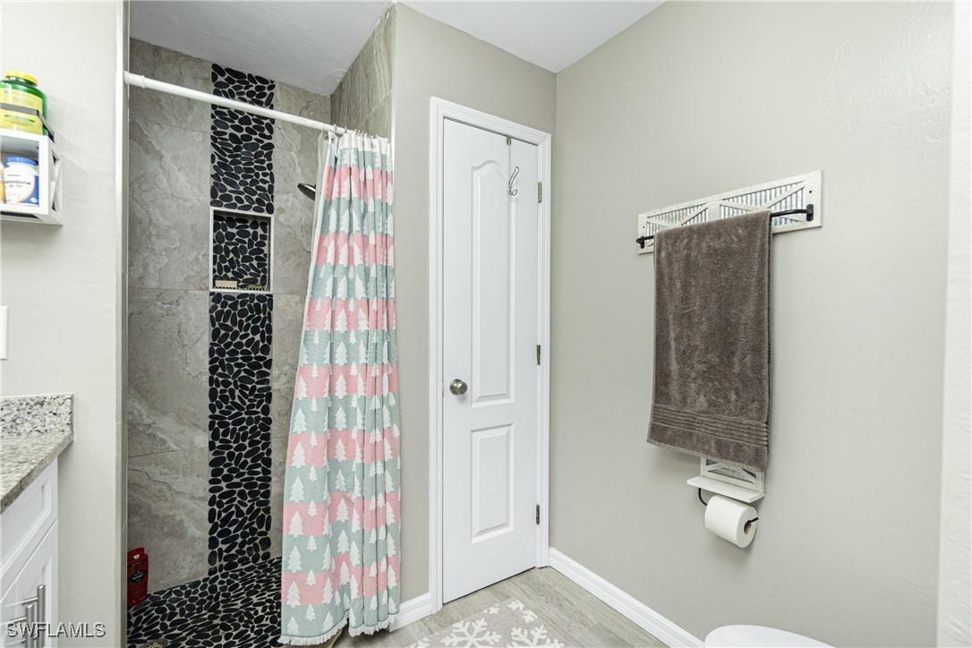 bathroom with a shower with shower curtain, vanity, and hardwood / wood-style flooring