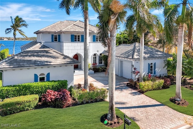 view of front of property featuring a water view, a garage, and a front lawn