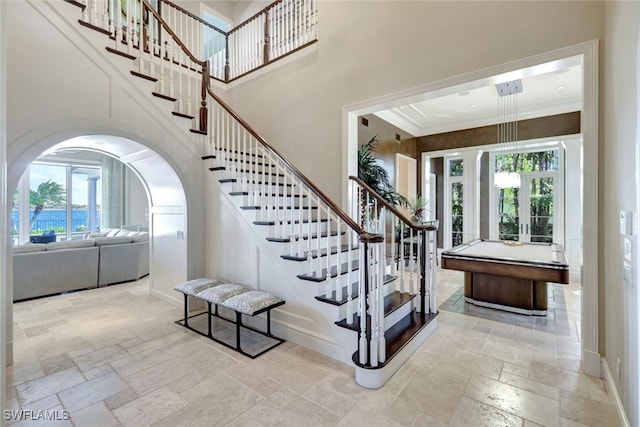 staircase featuring french doors, ornamental molding, and billiards