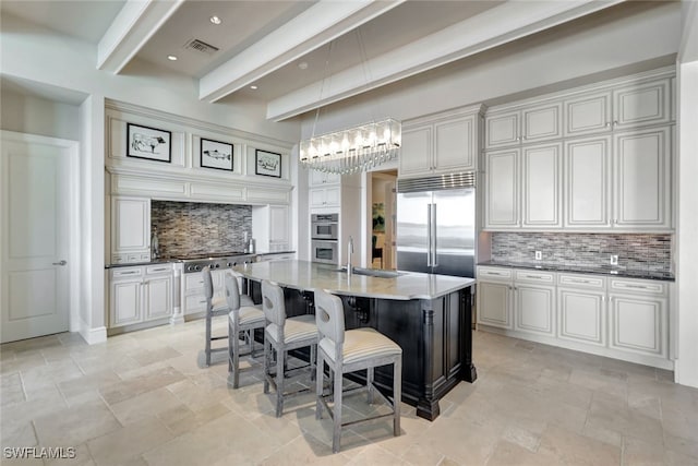 kitchen featuring a center island with sink, sink, hanging light fixtures, beamed ceiling, and stainless steel appliances