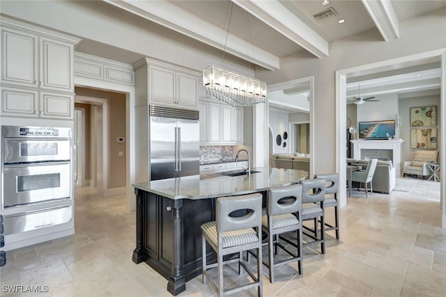 kitchen featuring light stone countertops, tasteful backsplash, stainless steel appliances, sink, and beamed ceiling