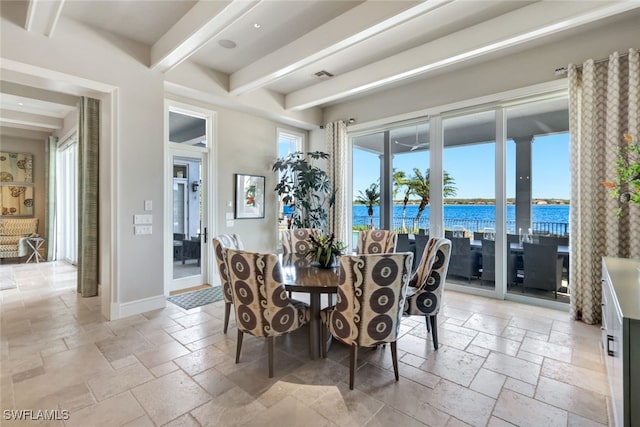 dining area with beamed ceiling and a water view