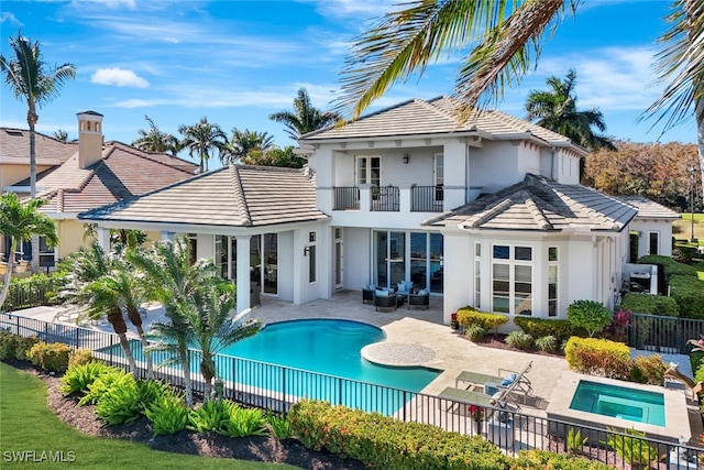 rear view of house with a patio, a balcony, and a pool with hot tub