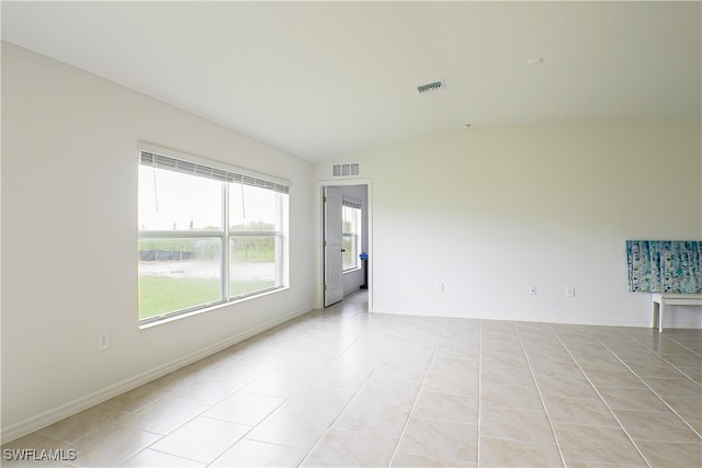 tiled spare room with vaulted ceiling