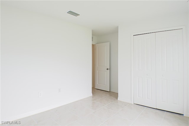 unfurnished bedroom featuring light tile patterned floors and a closet