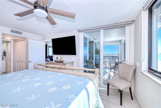 bedroom featuring ceiling fan, light hardwood / wood-style floors, access to exterior, and multiple windows