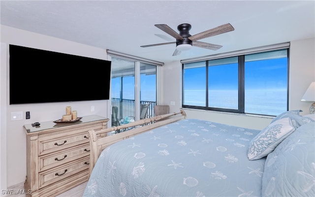 bedroom with access to exterior, a water view, and ceiling fan