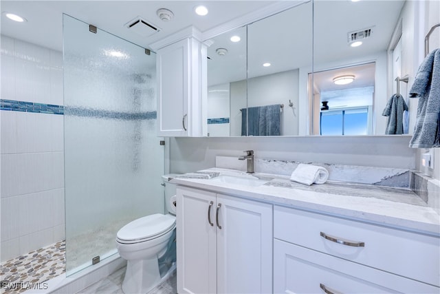 bathroom featuring a tile shower, vanity, and toilet