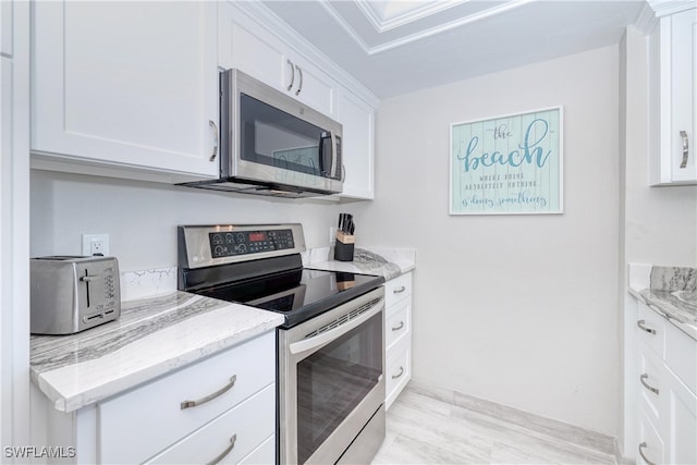 kitchen featuring white cabinets, light wood-type flooring, stainless steel appliances, and light stone counters